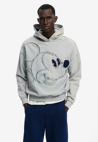 Sudadera gris claro con un diseño bordado de Mickey Mouse, con bordes deshilachados, capucha con cordón y un corte holgado.
