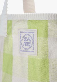 Borsa in tela con un motivo a quadretti verdi e bianchi, con un'etichetta tessuta che mostra del testo in viola. Manici bianchi resistenti.