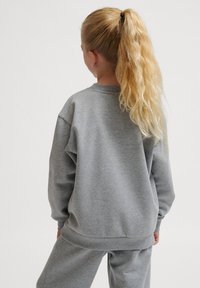 Hellgrauer Sweatshirt aus weichem Material, mit Rundhalsausschnitt, gerippten Bündchen und lockerer Passform. Kombiniert mit passenden Hosen.