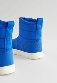 Blaue gepolsterte Knöchelstiefel mit glatter Oberfläche, flexibler Bauweise, strukturierten Akzenten und einer weißen Gummisohle.