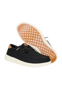 Scarpe da tennis nere con suola bianca, presentano un accento in pelle marrone sul tallone e una suola in gomma con motivo per garantire aderenza.