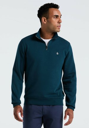 Türkiser Reißverschluss-Pullover aus weichem Stoff, mit hohem Kragen, gerippten Bündchen und einem kleinen Logo auf der Brust. Glatte Textur.