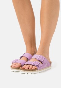 Lilac sandals with double adjustable straps, cork footbed, and textured rubber sole. Lightweight design suitable for casual wear.