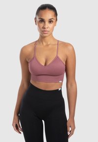 Stofzuigerroze ribgebreide bralette met verstelbare bandjes en een brede band. Gecombineerd met high-waisted zwarte leggings, wat een contrasterende look creëert.