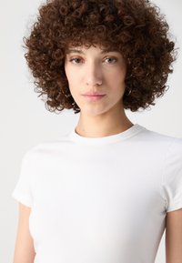 White cotton t-shirt with a crew neckline and short sleeves. Smooth texture, fitted design, no visible patterns or embellishments.