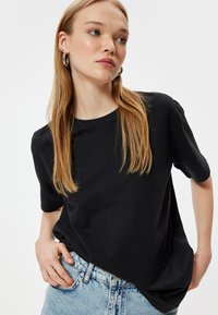 Sort kortærmet T-shirt med rund halsudskæring, lavet af blødt stof, parret med lyseblå denimjeans. Pasformen er afslappet og casual.