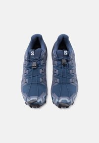 Ζευγάρι αθλητικών παπουτσιών μπλε και γκρι με μαύρα κορδόνια τραβήγματος, σε θέα από πάνω σε λευκό φόντο.