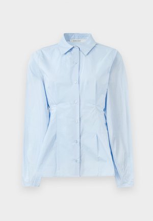 Chemise à manches longues bleu clair avec un col pointu, texture unie et coutures créant une coupe ajustée. Cinq boutons sur le devant.