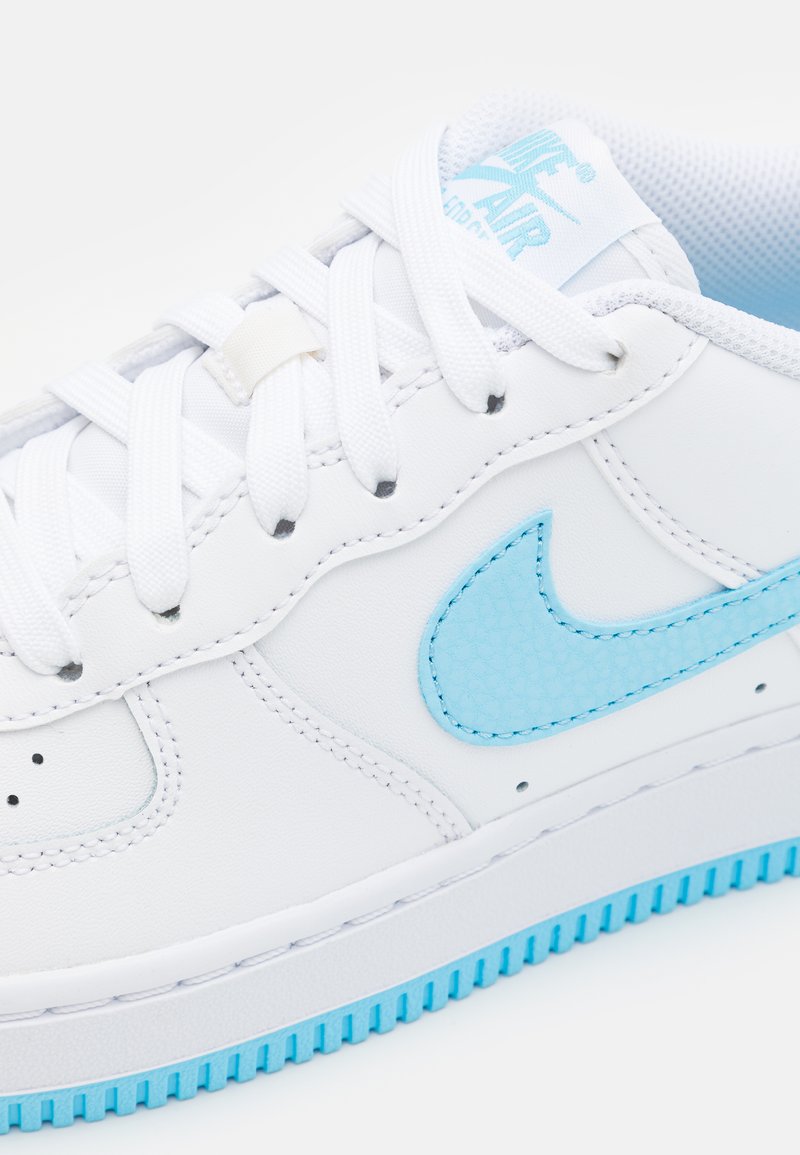Sneaker bianca con accenti azzurri. Realizzata in pelle liscia, presenta uno swoosh testurizzato e una suola in gomma con un motivo di battistrada azzurro chiaro.