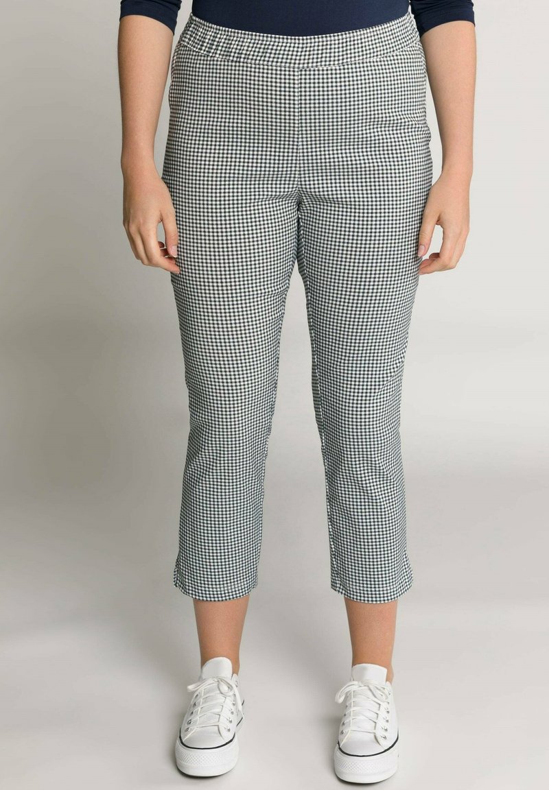 Pantaloni cropped in un motivo a quadri bianco e nero, con cintura elastica e design a gamba dritta, abbinati a sneaker bianche.