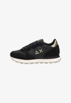 Zwarte sportieve sneakers met een gladde en suède textuur, witte zool, gouden accenten en logo-details aan de zijkant. Zijaanzicht.