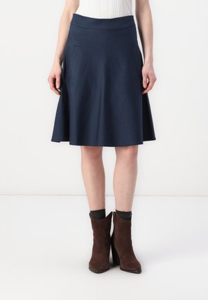 Navy A-line skirt with smooth fabric, wide waistband, and side pockets. Paired with brown suede ankle boots and dark socks.
