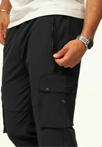 Schwarze Cargo-Hosen mit einem Reißverschluss-Seitentasche, strukturiertem Material und geknöpftem Cargo-Deckel. Mit Zugbanddetail und tailliertem Schnitt.