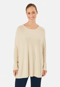 Helle beige, lockere Strickjacke aus weichem Stoff, mit einem runden Halsausschnitt und langen gerippten Ärmeln. Glatte Textur und lässiges Design.