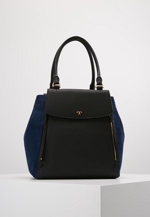 Zwarte leren en marineblauwe suède handtas met dubbele handvatten, voorflap, gouden ritssluitingdetails en klein gouden logo op een witte ondergrond.