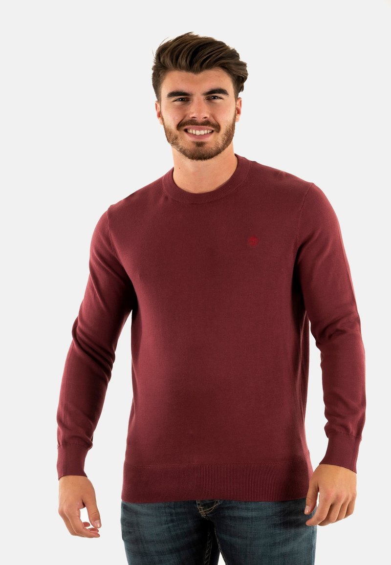 Maglione lavorato a maglia color bordeaux con scollatura a girocollo e maniche lunghe, dotato di polsini e orlo a coste, con un piccolo logo sul petto.