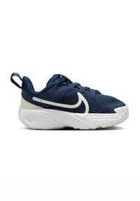 Zapatilla deportiva azul marino con parte superior texturizada, suela blanca y un acento verde. Cuenta con un collar acolchado y una cinta en el talón.