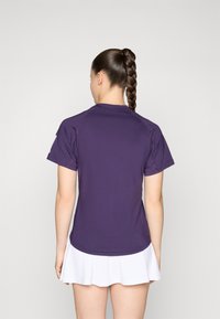 Paarse sportieve T-shirt met korte mouwen en een ronde hals. Glad materiaal met een getailleerd ontwerp, gecombineerd met een witte geplooide rok.