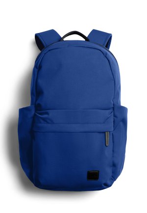 Sac à dos bleu avec bretelles rembourrées, poche zippée à l'avant et poignée de transport supérieure sur fond blanc.