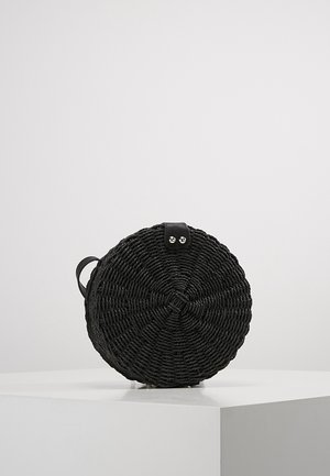 Ronde zwarte geweven handtas met een klein leren hengsel en een zilveren knoopsluiting, getoond op een wit oppervlak.