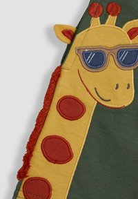Giraffe-thema patch in gele en oranje stof, met zonnebril, getextureerde wenkbrauwen en rode vlekken op een groene achtergrond.