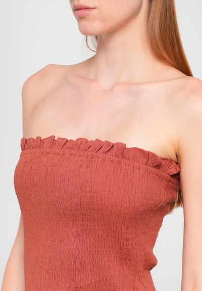 Ruched, strapless top in reddish-brown fabric with a textured surface and frilled edge. Fitted design contours the body.
