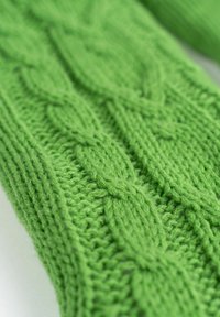 Helles grünes Strickgewebe mit einem strukturierten Zopfmuster, das glatte und gerippte Abschnitte für visuellen Kontrast kombiniert.