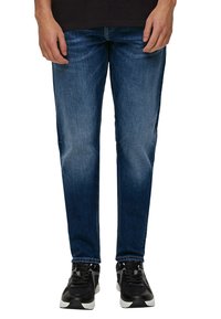 Dunkelblaue Jeans aus Denim mit regulärer Passform, die eine ausgewaschene Optik, ein Fünf-Taschen-Design und gestickte Details aufweisen, kombiniert mit schwarzen Sneakers.