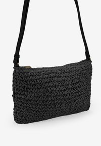 Borsa a tracolla intrecciata nera con un design testurizzato, caratterizzata da una forma rettangolare slim e un'unica tracolla regolabile. Finiture in metallo.