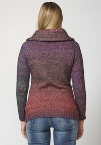 Neulepaita, jossa on leveä käännettävä kaulus, esittelee liukuvärjausta purppuran ja punaisen sävyissä, teksturoidulla pinnalla ja ribbaushelman kanssa.
