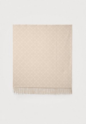 Couverture beige tissée avec un motif en losanges, finition avec des bords délicats en franges. Texture douce et forme rectangulaire.