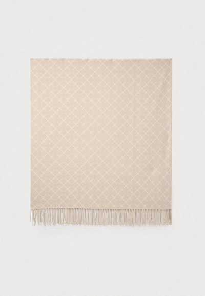 Couverture beige tissée avec un motif en losanges, finition avec des bords délicats en franges. Texture douce et forme rectangulaire.