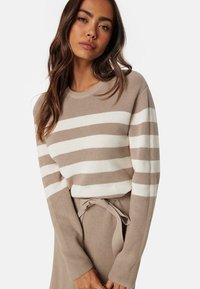 Maglione a righe beige e bianco in maglia con scollatura rotonda e maniche lunghe. Presenta una texture morbida e un motivo a coste.