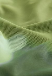 Zaļa sieta audums ar tekstūru, kas izstaro nelielu spīdumu. Materiāls izskatās viegls un elastīgs.