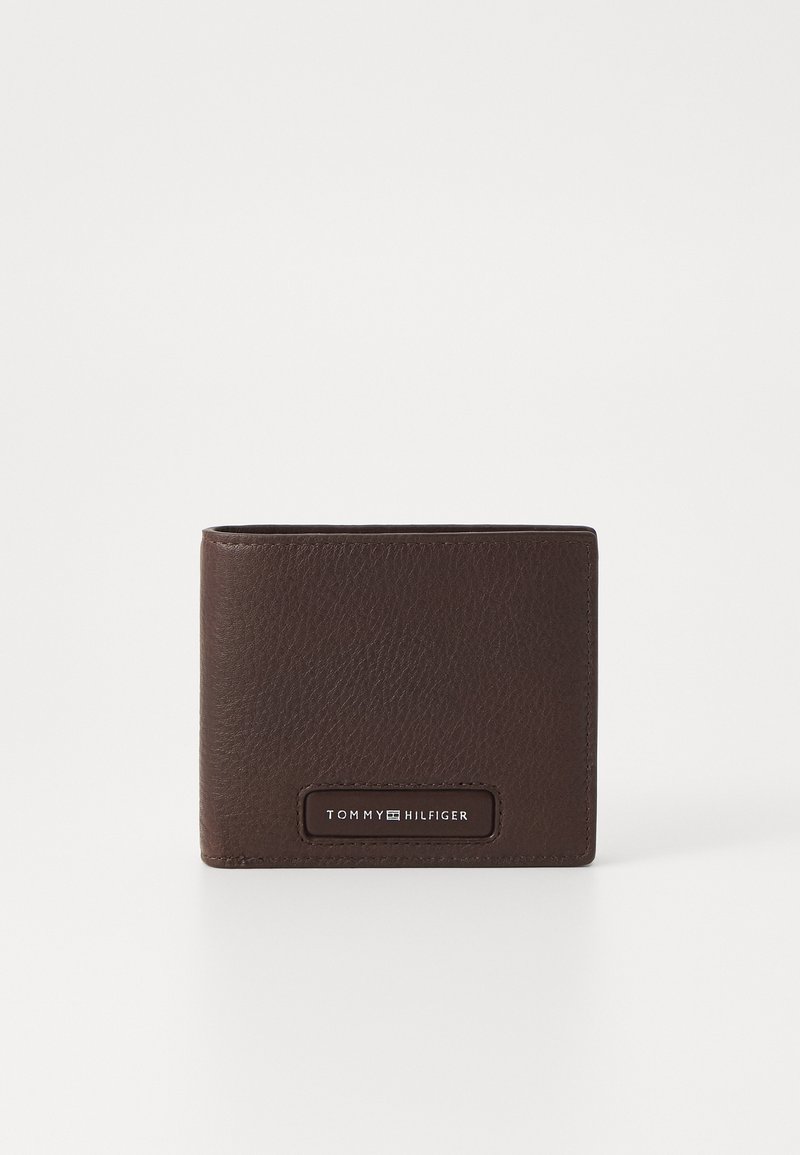 Portefeuille bi-fold en cuir marron avec une finition texturée. Présente une plaque-logo noire, mettant en avant un design minimaliste.