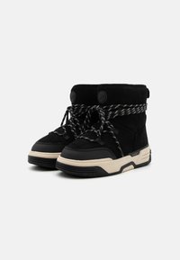 Bottes de cheville en suede noir avec des lacets tressés blancs et noirs, une semelle épaisse crème et des détails circulaires de logo noir sur les côtés.