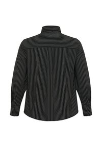 Black shirt featuring white vertical stripes, a collar, buttoned cuffs, and a relaxed fit. Fabric has a smooth texture.