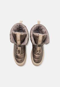 Izdaiļoti brūni zābaki ar spīdīgu apdari, kuriem ir quilted dizains, gaiši brūni akcenti, auklas aizdare un gumijas zole.