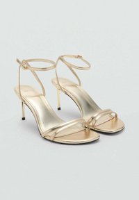 Gold metallic high-heeled sandals with thin ankle straps, open toe design, smooth texture, and a sleek stiletto heel.