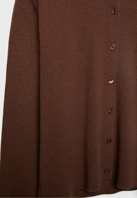 Cardigan marron en tricot avec des manches longues et une rangée de sept boutons foncés sur le devant.