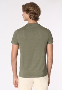 T-shirt a maniche corte verde oliva realizzato in un morbido tessuto testurizzato. Presenta un collo rotondo e una vestibilità comoda, visto da dietro.