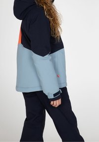 Farbenfrohe Jacke mit navyblauen, hellblauen und orangefarbenen Abschnitten. Sie hat eine Kapuze und dehnbare Bündchen und besteht aus wasserdichtem Material.