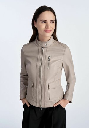 Beżowa skórzana kurtka z wysokim kołnierzem, z zamkiem błyskawicznym z przodu, dwoma bocznymi kieszeniami i subtelnym wzorem teksturowym na ramionach.