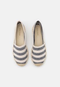 Espadrillas con una toma superiore in tela bianca caratterizzate da motivi a onde blu scuro, suole in juta intrecciata beige e una punta arrotondata.