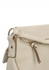 Bolso de mano de cuero crema con un acabado texturizado. Presenta un cierre de cremallera, herrajes en tono dorado y detalles de tiras de cuero anudadas.