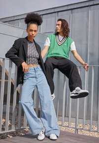 Sort-hvid mønstret crop top, oversized sort blazer, lyseblå vide bukser. Grøn strikket vest over hvid skjorte, sorte bukser og sneakers.