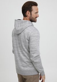 Gray patterned hoodie with a front kangaroo pocket, adjustable drawstring hood, and ribbed cuffs. Soft, textured fabric for comfort.