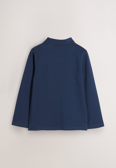 Tengerészkék, hosszú ujjú póló, pamutból. Vállal egy felhajtott gallért és egyenes alsó szegélyt, puha textúrával és finom varrási részletekkel.