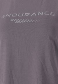 Lilla atletisk t-shirt lavet af blødt stof, med et skærmtrykt "ENDURANCE" logo i hvid, med en glat tekstur og korte ærmer.