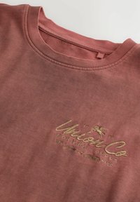 Staubig-rosafarbenes Sweatshirt mit Rundhalsausschnitt, beiger Stickerei und kleinem geflügeltem Pferdelogo auf der Brust.